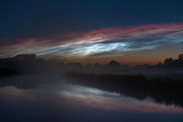 noctilucent clouds over foggy river