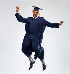 education, graduation and people concept - happy smiling indian male graduate student in mortar...