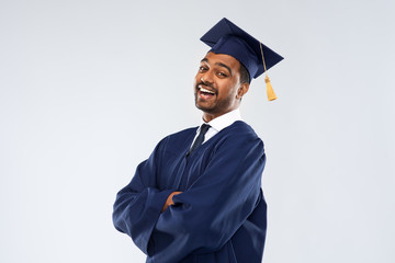 education, graduation and people concept - happy smiling indian male graduate student in mortar...