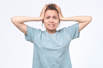 Girl screaming in terror with hands on her head, looking in panic at the camera.