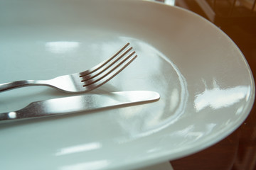 fork and knife on white plate in restaurant 