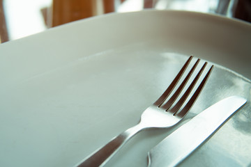 fork and knife on white plate in restaurant
