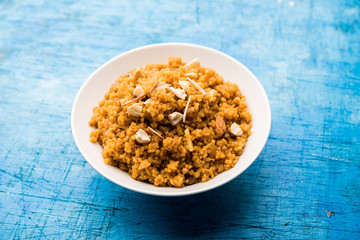 Wheat Laapsi/Lapsi/Shira/Halwa is an Indian sweet dish made of broken wheat or Daliya pieces and ghee along with nuts, raisins and dried fruits. It's a healthy food. served in a bowl, selective focus