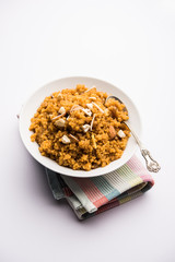 Wheat Laapsi/Lapsi/Shira/Halwa is an Indian sweet dish made of broken wheat or Daliya pieces and ghee along with nuts, raisins and dried fruits. It's a healthy food. served in a bowl, selective focus