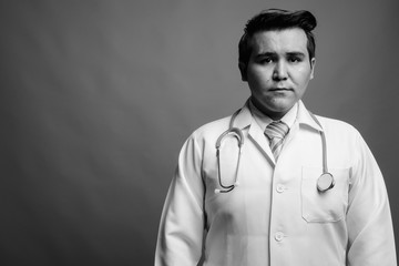 Young multi-ethnic man doctor against gray background