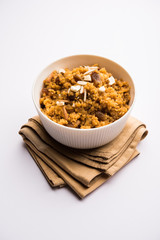 Wheat Laapsi/Lapsi/Shira/Halwa is an Indian sweet dish made of broken wheat or Daliya pieces and ghee along with nuts, raisins and dried fruits. It's a healthy food. served in a bowl, selective focus
