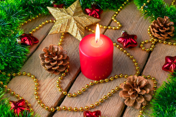 Christmas background. Christmas decorations with cones and a candle on a wooden background. Red color.