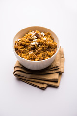 Wheat Laapsi/Lapsi/Shira/Halwa is an Indian sweet dish made of broken wheat or Daliya pieces and ghee along with nuts, raisins and dried fruits. It's a healthy food. served in a bowl, selective focus