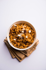 Wheat Laapsi/Lapsi/Shira/Halwa is an Indian sweet dish made of broken wheat or Daliya pieces and ghee along with nuts, raisins and dried fruits. It's a healthy food. served in a bowl, selective focus