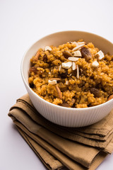 Wheat Laapsi/Lapsi/Shira/Halwa is an Indian sweet dish made of broken wheat or Daliya pieces and ghee along with nuts, raisins and dried fruits. It's a healthy food. served in a bowl, selective focus