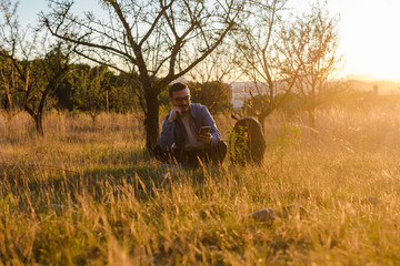 Naklejka na ściany i meble Young man is using his smartphone in a meadow