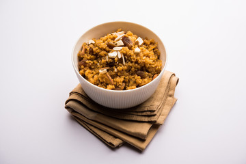 Wheat Laapsi/Lapsi/Shira/Halwa is an Indian sweet dish made of broken wheat or Daliya pieces and ghee along with nuts, raisins and dried fruits. It's a healthy food. served in a bowl, selective focus