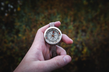 Man hand holding a old compass with broken glass. Travel concept, path selection, navigation, tourism, hiking. Autumn background. crack on the glass as disappointment and cancellation of plans.