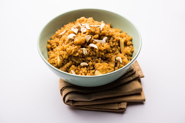 Wheat Laapsi/Lapsi/Shira/Halwa is an Indian sweet dish made of broken wheat or Daliya pieces and ghee along with nuts, raisins and dried fruits. It's a healthy food. served in a bowl, selective focus