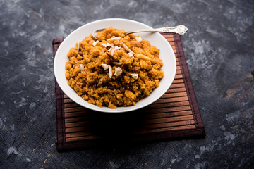 Wheat Laapsi/Lapsi/Shira/Halwa is an Indian sweet dish made of broken wheat or Daliya pieces and ghee along with nuts, raisins and dried fruits. It's a healthy food. served in a bowl, selective focus