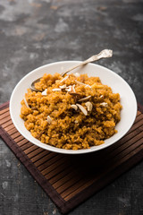 Wheat Laapsi/Lapsi/Shira/Halwa is an Indian sweet dish made of broken wheat or Daliya pieces and ghee along with nuts, raisins and dried fruits. It's a healthy food. served in a bowl, selective focus