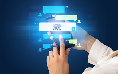 Female hand typing on smartphone with GONE VIRAL inscription, social networking concept