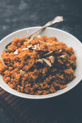 Wheat Laapsi/Lapsi/Shira/Halwa is an Indian sweet dish made of broken wheat or Daliya pieces and ghee along with nuts, raisins and dried fruits. It's a healthy food. served in a bowl, selective focus