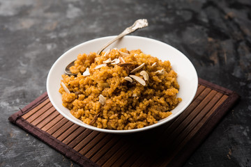Wheat Laapsi/Lapsi/Shira/Halwa is an Indian sweet dish made of broken wheat or Daliya pieces and ghee along with nuts, raisins and dried fruits. It's a healthy food. served in a bowl, selective focus