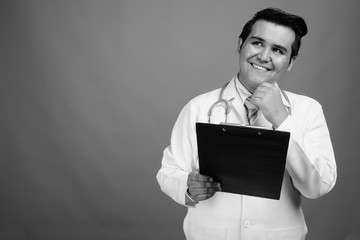 Young multi-ethnic man doctor against gray background