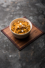 Wheat Laapsi/Lapsi/Shira/Halwa is an Indian sweet dish made of broken wheat or Daliya pieces and ghee along with nuts, raisins and dried fruits. It's a healthy food. served in a bowl, selective focus