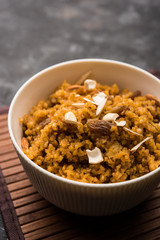Wheat Laapsi/Lapsi/Shira/Halwa is an Indian sweet dish made of broken wheat or Daliya pieces and ghee along with nuts, raisins and dried fruits. It's a healthy food. served in a bowl, selective focus