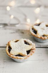 Mince pie served on wooden table, Christmas lights on background. Typical winter dessert