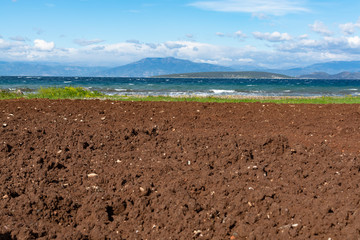 Agriculture in Greece, plowed field with fertile soil and sea water nearby