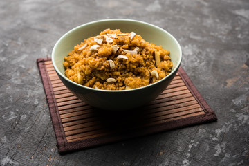 Wheat Laapsi/Lapsi/Shira/Halwa is an Indian sweet dish made of broken wheat or Daliya pieces and ghee along with nuts, raisins and dried fruits. It's a healthy food. served in a bowl, selective focus