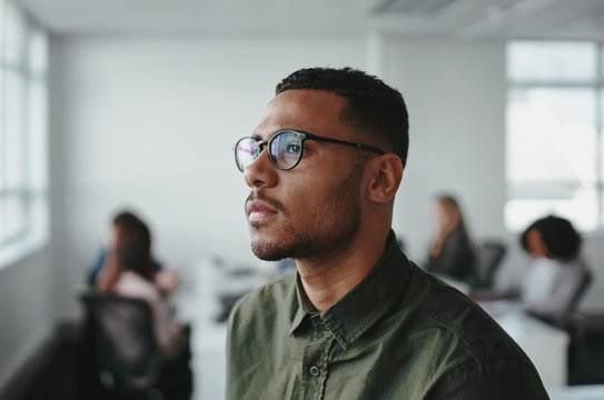 Close-up of a young african american business man entrepreneur wearing eyeglasses contemplating in office