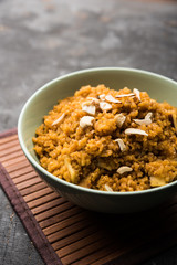 Wheat Laapsi/Lapsi/Shira/Halwa is an Indian sweet dish made of broken wheat or Daliya pieces and ghee along with nuts, raisins and dried fruits. It's a healthy food. served in a bowl, selective focus
