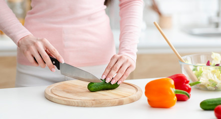 Obraz na płótnie Canvas Woman cutting fresh vegetables for salad on wooden board