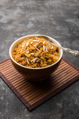 Wheat Laapsi/Lapsi/Shira/Halwa is an Indian sweet dish made of broken wheat or Daliya pieces and ghee along with nuts, raisins and dried fruits. It's a healthy food. served in a bowl, selective focus