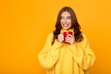 Woman wearing sweater and hold cup, orange background