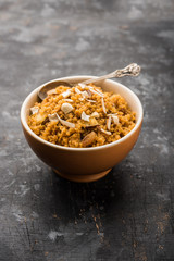 Wheat Laapsi/Lapsi/Shira/Halwa is an Indian sweet dish made of broken wheat or Daliya pieces and ghee along with nuts, raisins and dried fruits. It's a healthy food. served in a bowl, selective focus