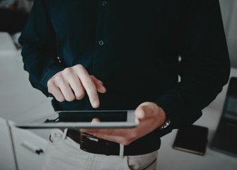 Mid section of a well dressed businessman touching his digital tablet screen with finger