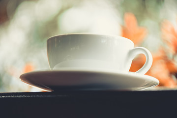 Closeup of  white coffee cup On a wooden table in the morning time, vintage style.(selective focus)