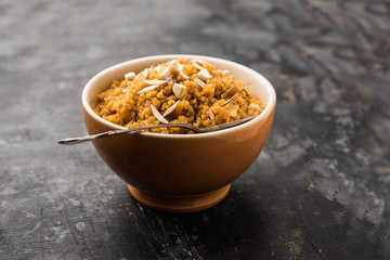 Wheat Laapsi/Lapsi/Shira/Halwa is an Indian sweet dish made of broken wheat or Daliya pieces and ghee along with nuts, raisins and dried fruits. It's a healthy food. served in a bowl, selective focus