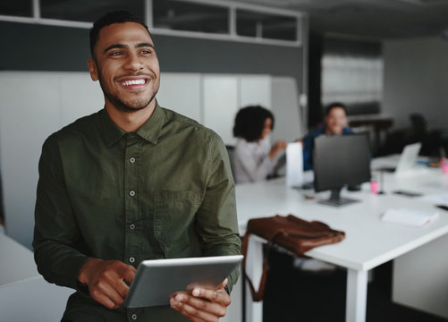 Portrait of a young creative business owner holding digital tablet in hand smiling and looking away - Powered by Adobe
