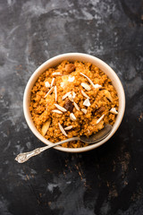 Wheat Laapsi/Lapsi/Shira/Halwa is an Indian sweet dish made of broken wheat or Daliya pieces and ghee along with nuts, raisins and dried fruits. It's a healthy food. served in a bowl, selective focus