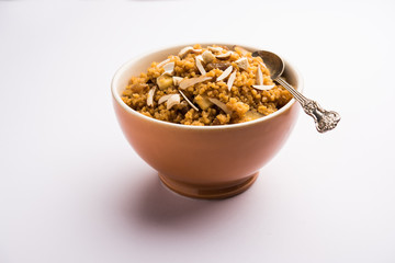 Wheat Laapsi/Lapsi/Shira/Halwa is an Indian sweet dish made of broken wheat or Daliya pieces and ghee along with nuts, raisins and dried fruits. It's a healthy food. served in a bowl, selective focus