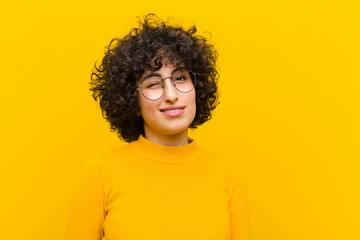young pretty afro woman looking happy and friendly, smiling and winking an eye at you with a...