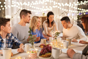 celebration and family concept - happy man blowing candles on birthday cake at dinner party at home