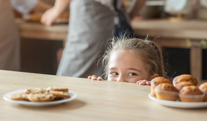 Cute little girl looking with joy at sweets
