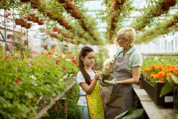 Grandmother and her grandchild enjoying in the garden with flowers