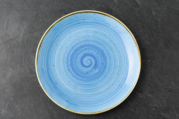 table setting, tableware and eating concept - close up of blue ceramic plate on slate background