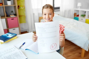 children, education and learning concept - student girl with good mark on school test at home