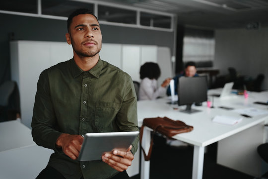 Thoughtful Young Businessman Thinking On Productive Strategy Using Digital Touch Pad Device In Modern Office