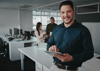 Portrait of a confident corporate executive using a digital tablet in a modern office looking at...