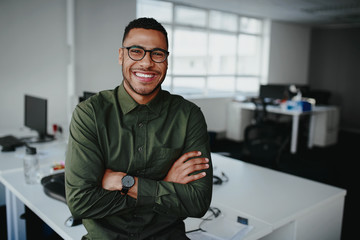 Portrait of a happy confident young african american businessman standing with his arms crossed looking at camera - 292950930